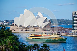 Green ferry boat in Sydney harbour with Opera house at the background.